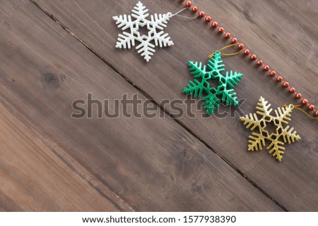 Christmas and Holiday Season Concept. Top view of xmas snow flake ornament and red beads accessories  on old wooden plank with copy space.