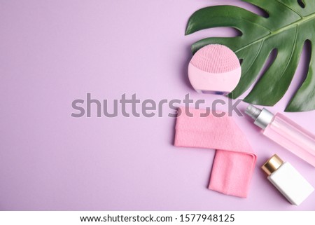 Flat lay composition with face cleansing brush on violet background, space for text. Cosmetic accessory