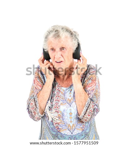 Annoyed senior woman wearing headphones against a white background