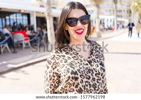 Young beautiful woman with red lips wearing sunglasses smiling happy at the street