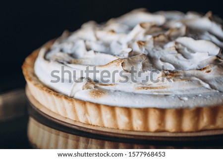 Tasty lemon meringue pie. Traditional french sweet pastry tart. Delicious, appetizing, homemade dessert with lemon cream. Copy space, closeup. Selective focus. Black background. Toned