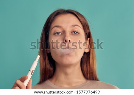 Electronic Cigarette Technology. Tobacco IQOS system. Close-up of a girl smoking an electric hybrid cigarette with a heating pad. tobacco heating system.