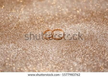 gold wedding rings on the glitter sparkle background