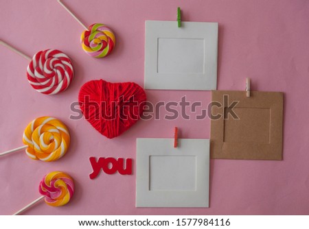 Festive background decoration for birthday celebration, Valentines day with red love lettering, heart shaped and colorful lollipop candies on pink paper background. Top view.