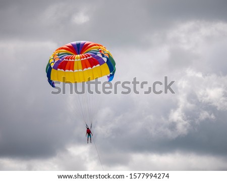 Anonymous parasail rider flies in free endless cloudy sky empty space colorful