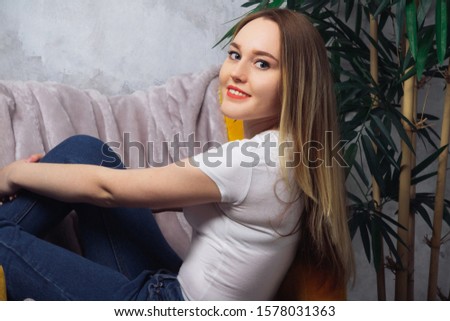 Beautiful girl sitting in a chair next to a house plant