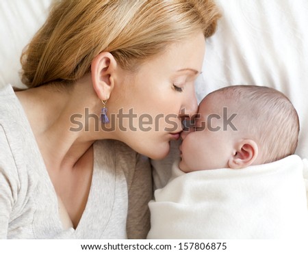 blond young mother with her baby lying in the bed