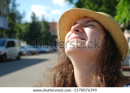 Portrait of a young girl wich looks at the sun in a sunhat.