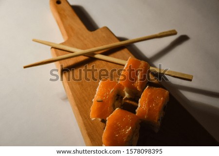 Sushi roll japanese food in restaurant. California Sushi roll set with salmon, vegetables, red flying fish roe. Sushi with chopsticks. Top view. Copyspase. Japan restaurant menu cuisine. Wood board 