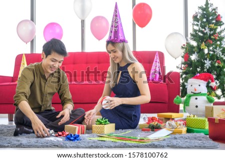 Beautiful young couple is making a gift box