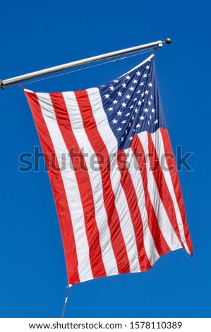 US Flag with Stars and Strips with blue Sky hanging from a Building in Manhattan New York