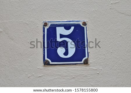 
A house number plaque, showing the number five (5)