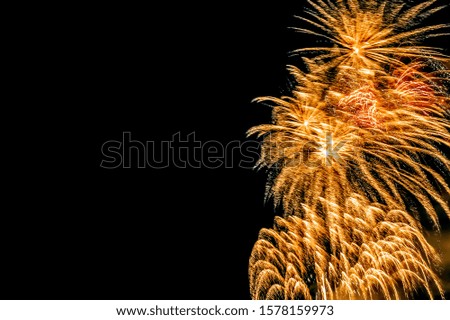 Several festive explosions of golden fireworks in the dark sky during celebration with copy space. Christmas, New Year, Independence Day, Valentine's Day, birthday, anniversary greeting card concept.