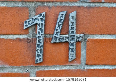 A house number plaque, showing the number fourteen (14)
