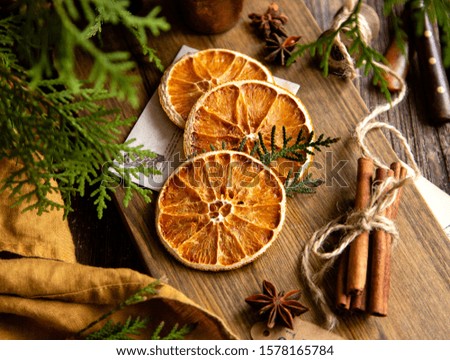 dried orange slices on wooden board with anise stars, cinnamon sticks, fir tree branches, ingredients for cooking or christmas decoration Royalty-Free Stock Photo #1578165784