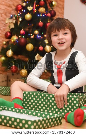 Happy little boy open Christmas gift. Child with presents under a Christmas tree