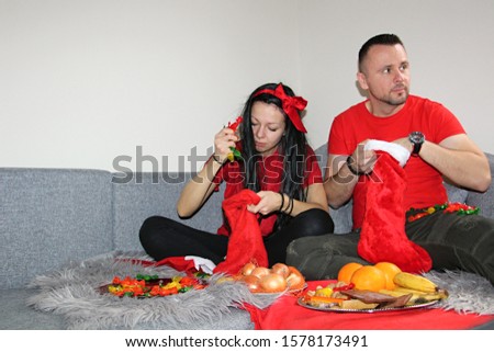 nice pair putting candies and fruits in santa boots for saint nicholas day