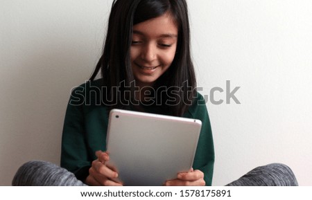 Technology and people concept. Kids girl using tablet computer over grey background.