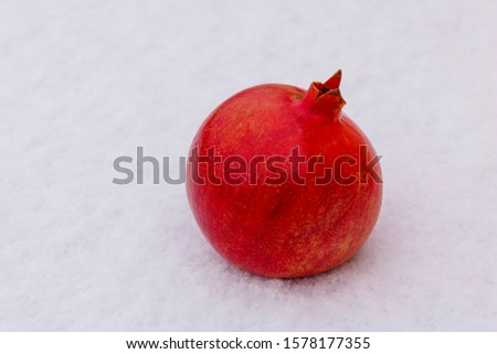 pomegranate fruit lies on the white snow