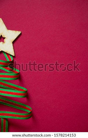 Minimal winter creative table flat lay, Christmas tree made of ribbon and wooden star and gift figurines