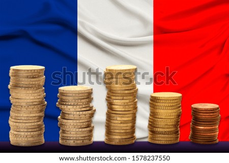 stacks of euro currency coins against the background of the silk flag of France, the concept of financial growth, the dynamics of the national currency, financial devaluation, inflation