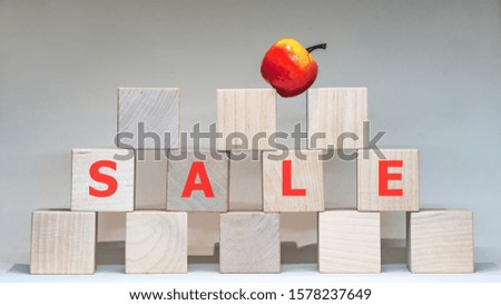 Word Sale with wooden letters with apple on top on a white background.