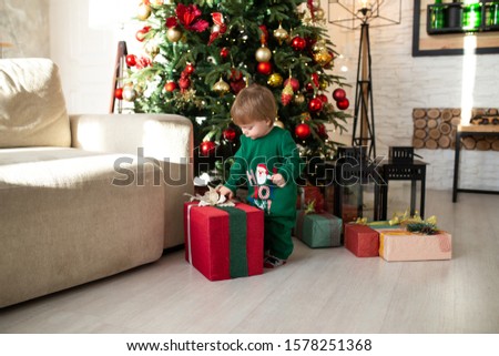 Happy little smiling boy playing with Christmas gift boxes