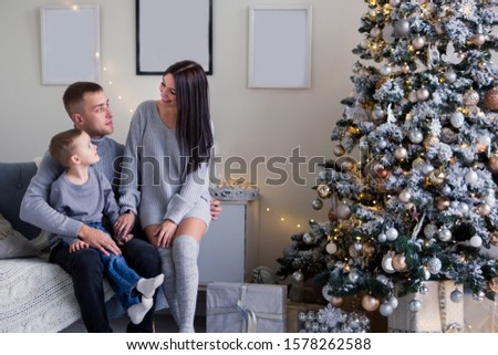 Christmas family life photo. photo of a beautiful young family with a son in gray clothes