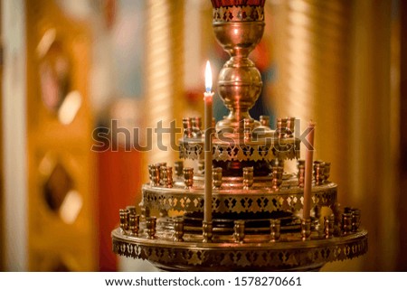 symbol of faith and Christianity: a candlestick with burning candles in the temple in darkness
