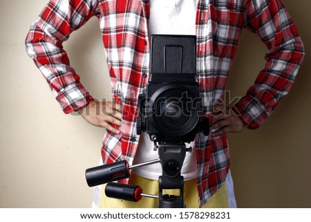 Photo of an adult man holding an old and vintage medium format film camera on a tripod.