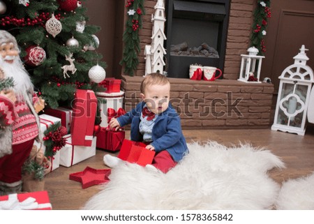 Little boy plays with presents in a room decorated on the eve of Christmas