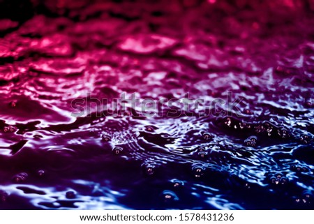 natural black water surface wave background with blurred filter for soft motion abstract white bubble reflexing with trendy neon light of dark navy blue gradient to pink color graphic with copy space
