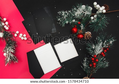 Christmas minimal mockup - red xmas balland firtree on black background. Horizontal composition with empty paper blank. Flat lay, top view.