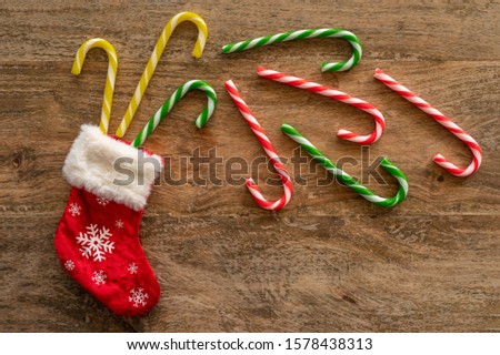 Christmas sock and Christmas candies on wooden background.