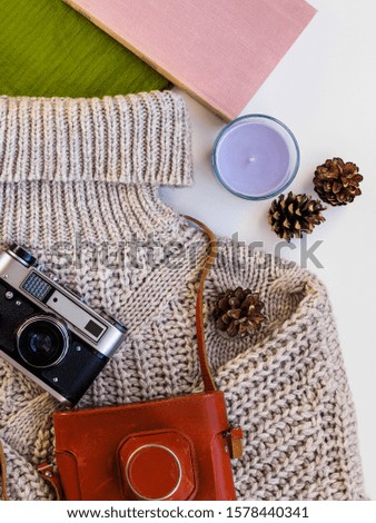 Old camera, books and warm clothes on the table.