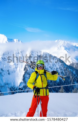 Portrait of sportive man in helmet with skis on his shoulder