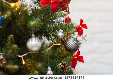 Beautiful green Christmas tree decorated with gray balls and garlands. Close-up photo. Sparkling background