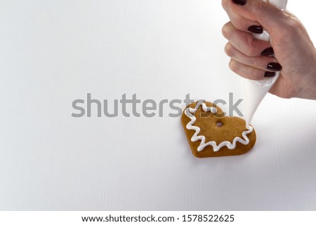 female hand draws white icing on gingerbread cookies. copy space
