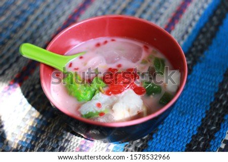 Es Oyen Bandung. Popular iced dessert from Bandung, consists of coconut, jackfruit, tapioca pearls, and avocado in sweetened coconut milk. Served in a ceramic bowl on a rustic wooden table

