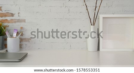 Cropped shot of comfortable workplace with mockup frame, office supplies and copy space on white table