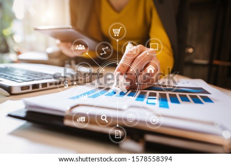 Businesswoman hand working digital marketing media in virtual screen with mobile phone and modern compute with VR icon diagram at office in morning light 