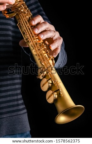 soprano saxophone in the hands of a guy on a black background Royalty-Free Stock Photo #1578562375