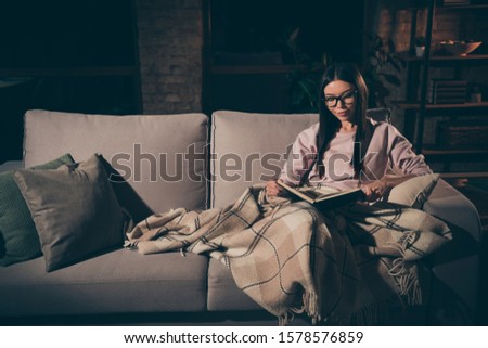 Photo of homey lady can't sleep until read love novel to end interested book worm addiction sitting couch covered warm blanket casual clothes spectacles dark living room indoors
