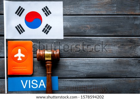 Visa to Korea concept. Korean flag near passport and judge hammer on dark wooden background top-down copy space