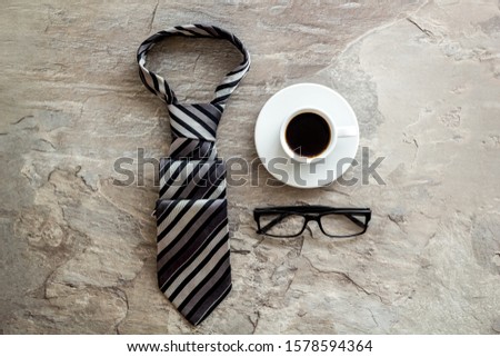 Father's birthday concept. Men's tie, coffee, glasses on grey background top-down