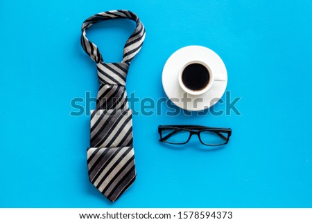 Father's birthday concept. Men's tie, coffee, glasses on blue background top-down