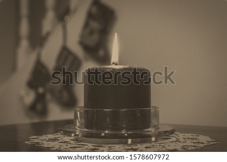 Vintage photo of a burning candle with Christmas stockings in the background