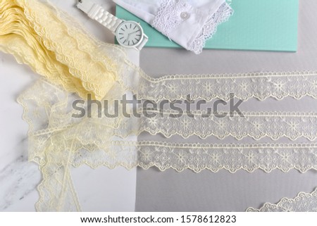 Texture of illuminated yellow lace fabric and white watch on ultimate gray background. Use for clothes and sew. space for text.