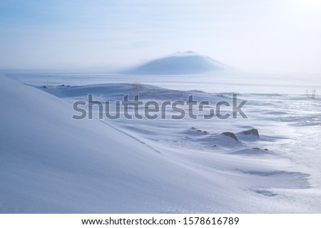 Winter arctic landscape with snow covered tundra and hills. Very cold frosty weather in April in the far north of Russia. Location place: Chukotka, Siberia, Russian Far East. Polar region. Royalty-Free Stock Photo #1578616789