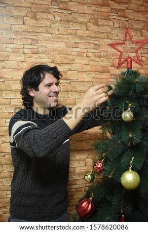 Man decorates a Christmas tree for New Year. Last preparation for Christmas